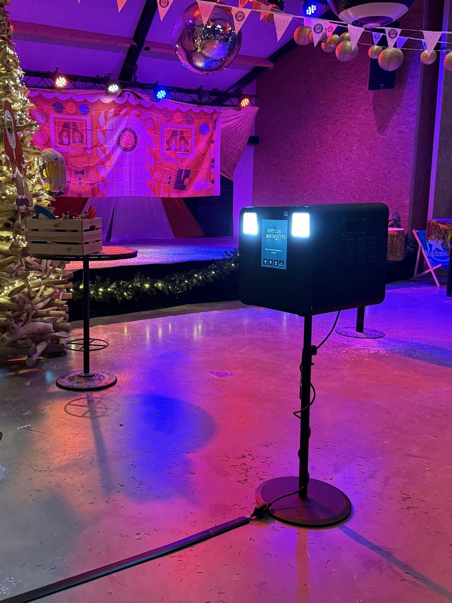 Photobooth opgesteld in een feestzaal met discobal en gekleurd licht, klaar voor de gasten