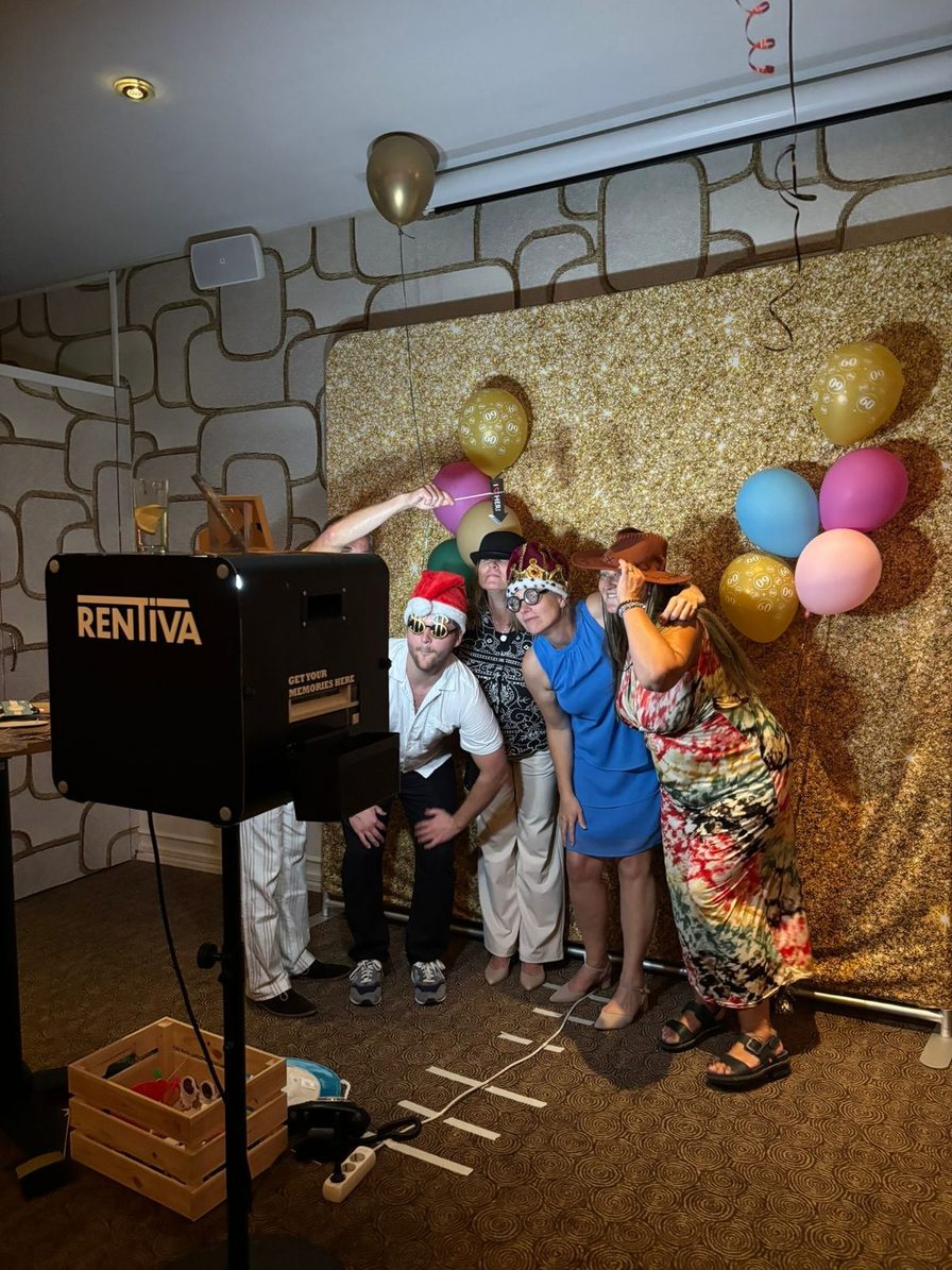 Gasten poseren met hoedjes voor de photobooth op een verjaardag met ballonnen en een gouden achterwand